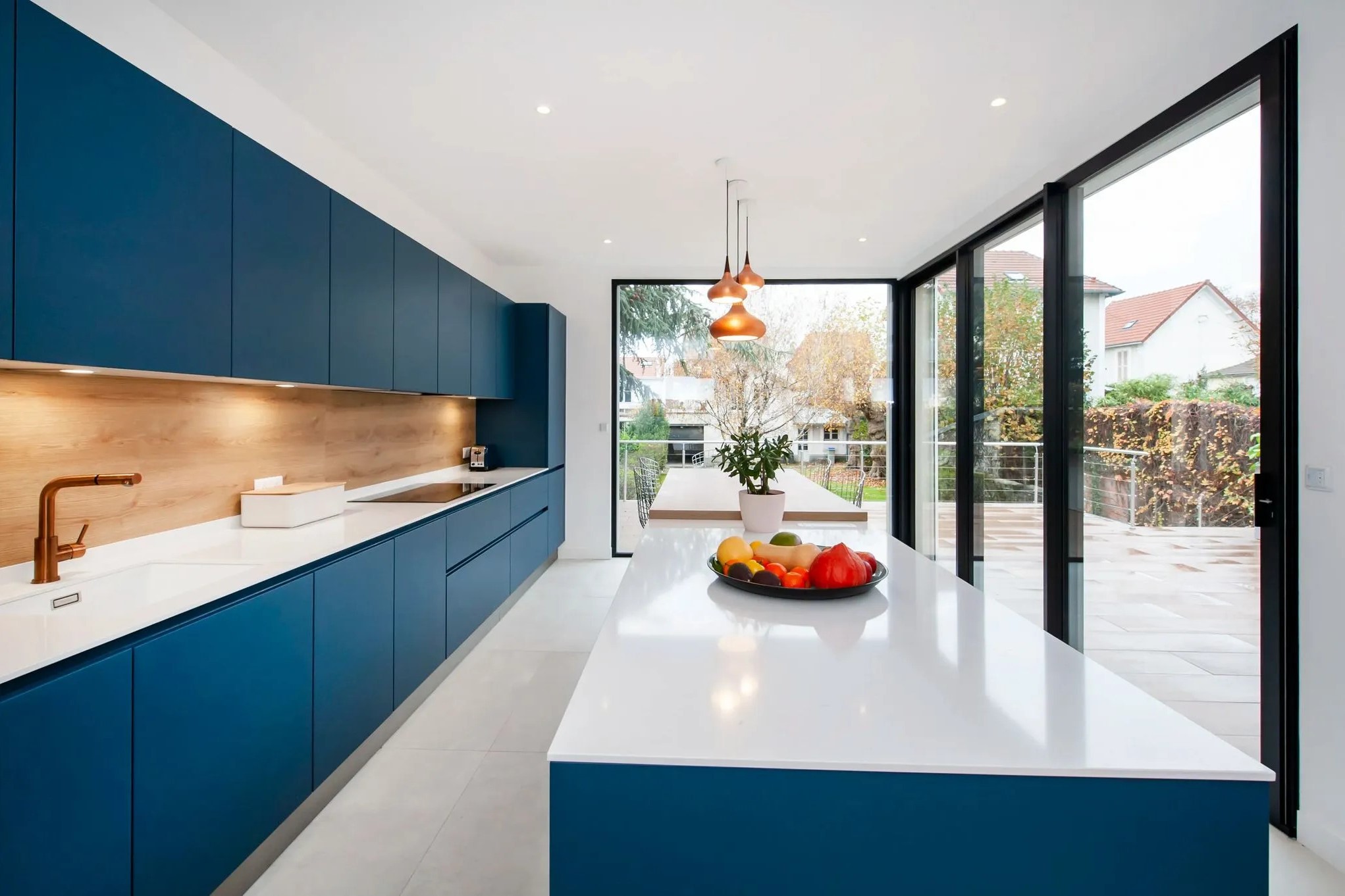 cuisine bleue ouverte sur l'extérieur avec grande baie vitrée 