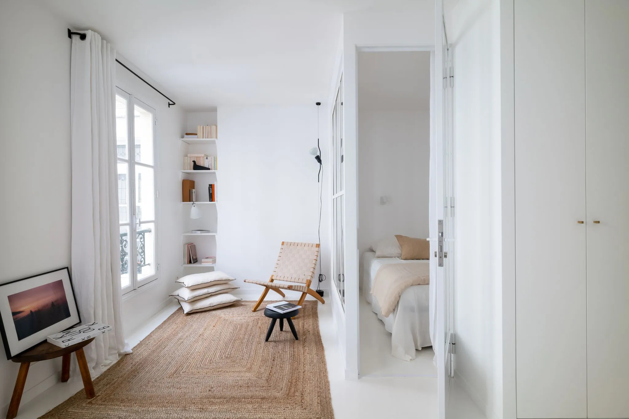 Salon blanc avec tapis en jonc de mer et bibliothèque dans une niche