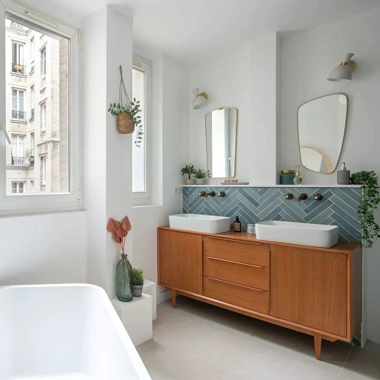 Une salle de bains avec baignoire et meuble vasque, zellige bleu posé en chevron en crédence