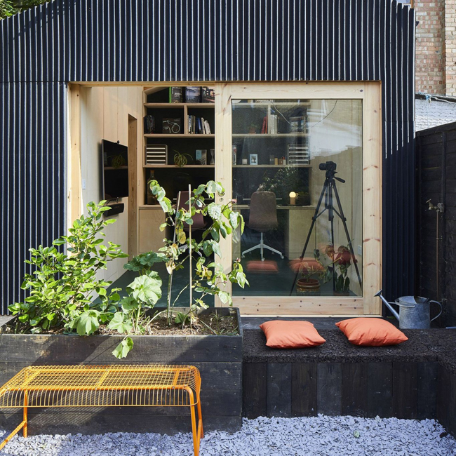 Bureau installé dans un studio de jardin avec un bardage en bois noir