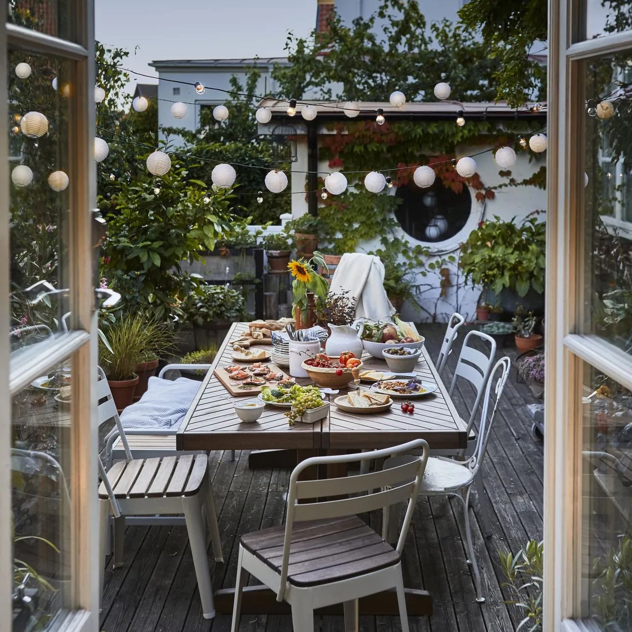 Terrasse en bois avec table en métal et guirlandes lumineuses
