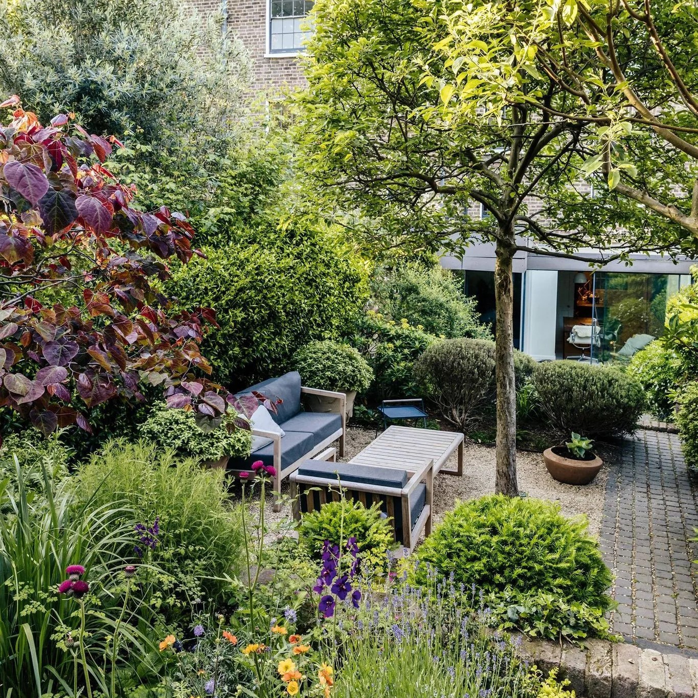 Jardin ombragé aménagé avec un salon et des allées en pierres incrustées