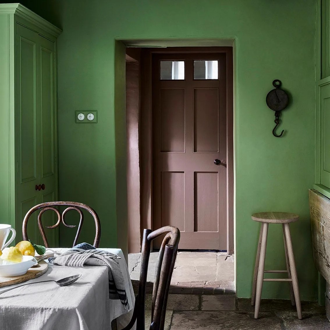 Cuisine avec mur vert et porte marron