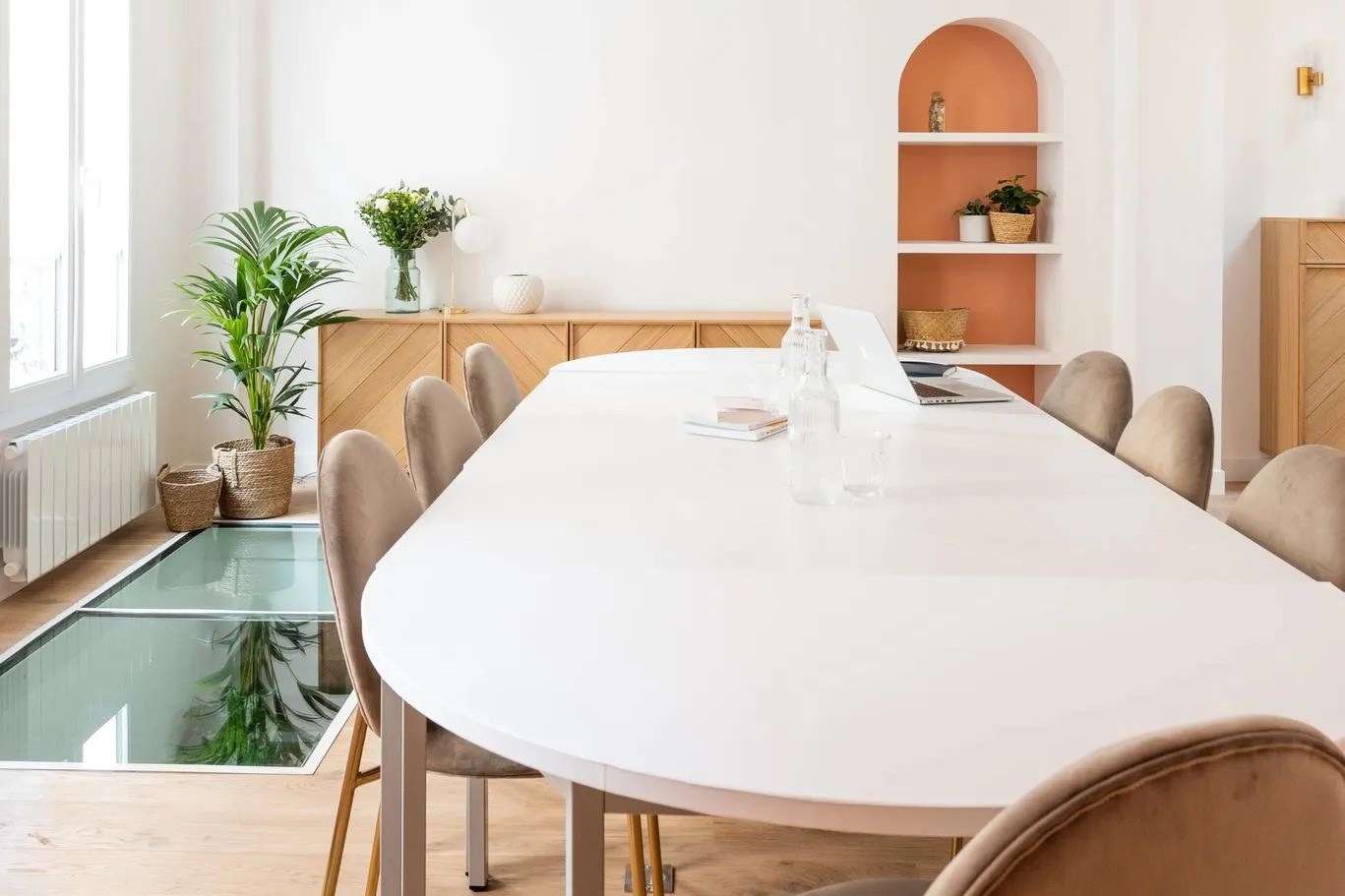 Une grande table de bureaux professionnels, pavé de verre au sol, alcôve colorée