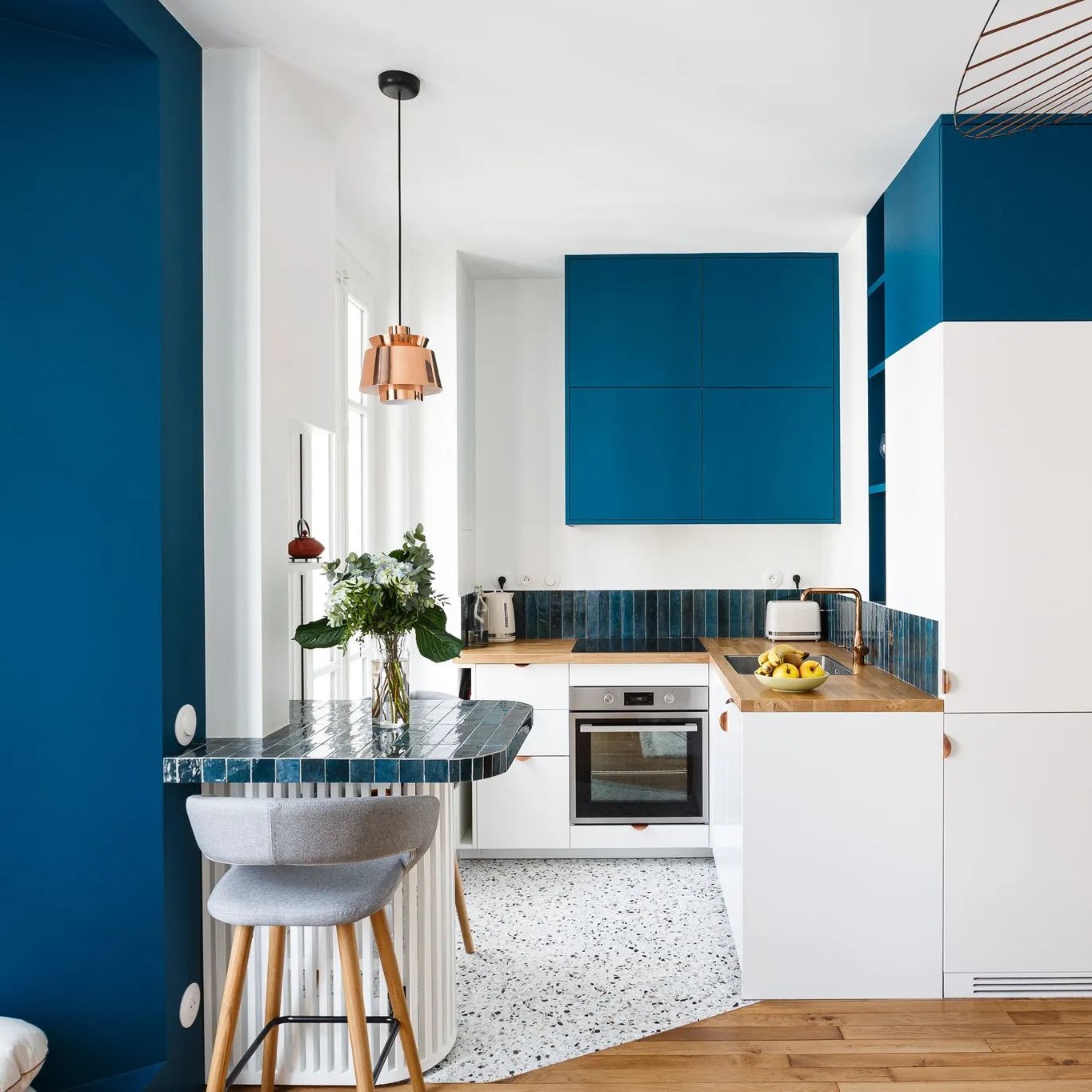 Cuisine ouverte avec murs bleu et blanc terrazzo